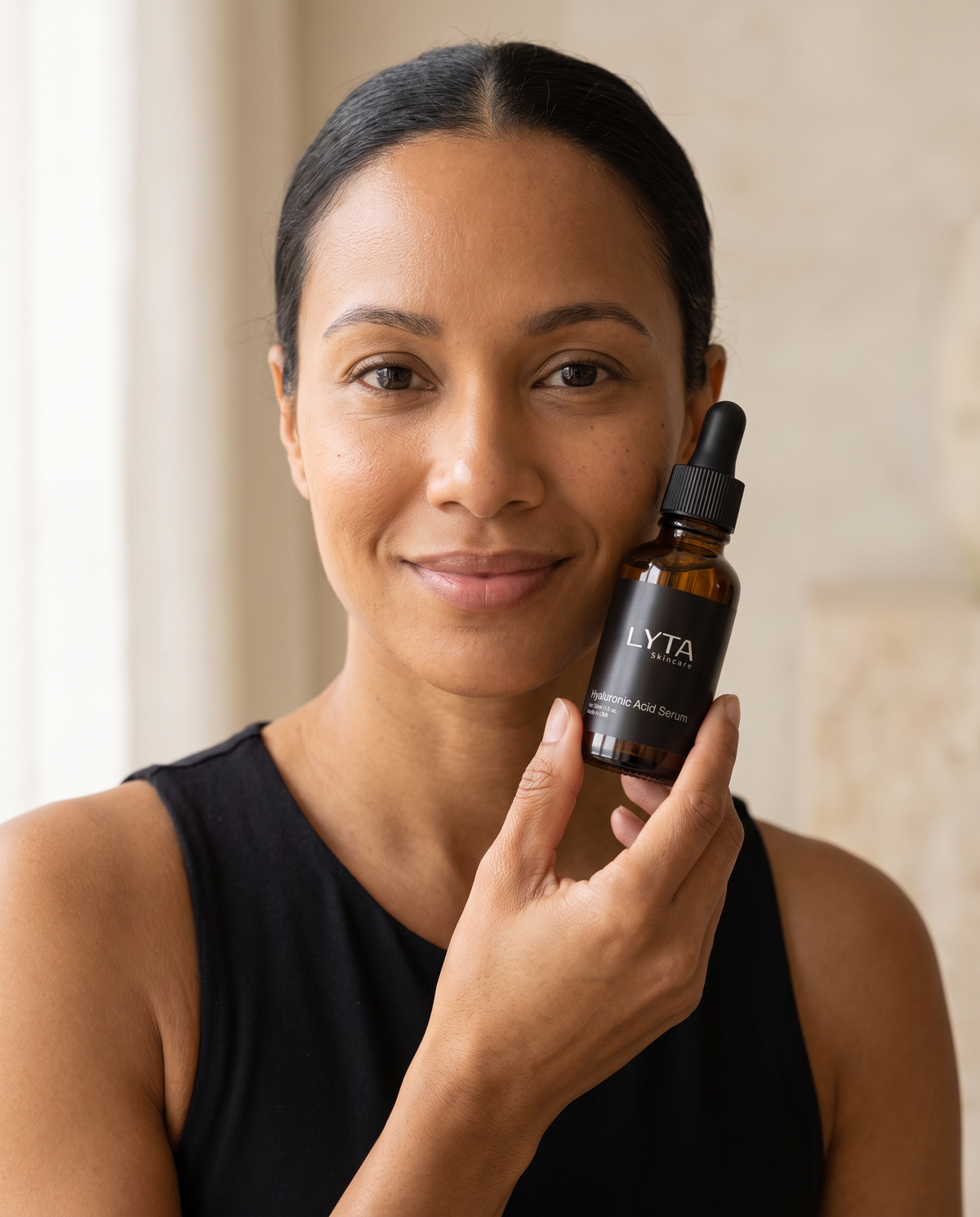 Adult model holding the actual LYTA Hyaluronic Acid Serum dropper bottle