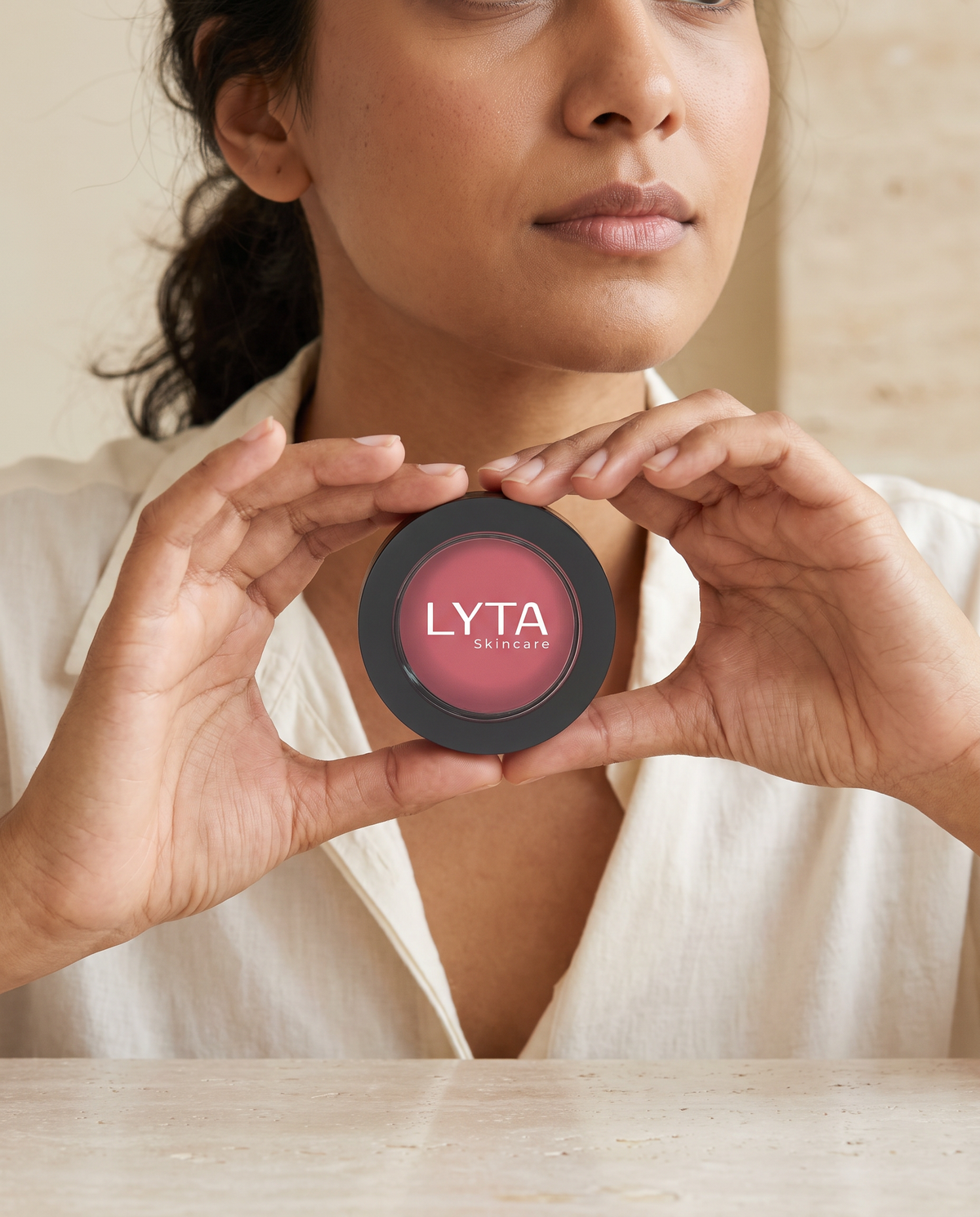 LYTA Single Pan Blush in Lotus, model holding the original closed branded compact