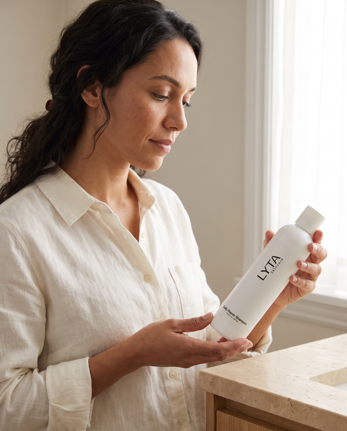 LYTA Daily Repair Shampoo, model holding the original closed white bottle