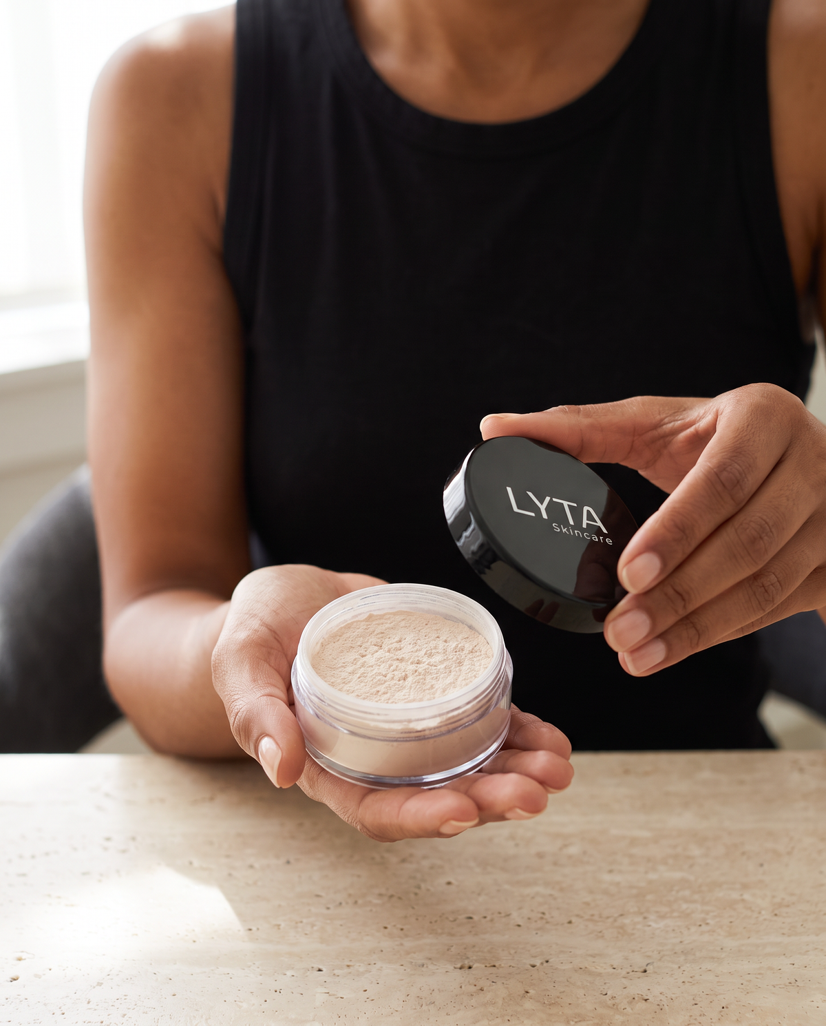 LYTA Finishing Powder held in hand, showing the original clear jar and black lid